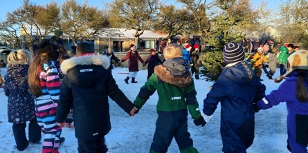 Børn hånd i hånd i en snedækket skolegård