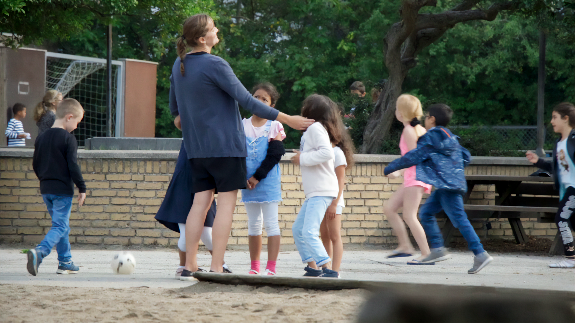 En lærer med glade børn i skolegården på Tilst Skole